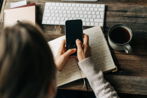 aerial view of person using cell phone on top of planner with computer