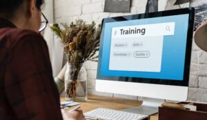 Woman at computer doing with the words Training, Experience, Knowledge, Wisdom, Skills and Quality.